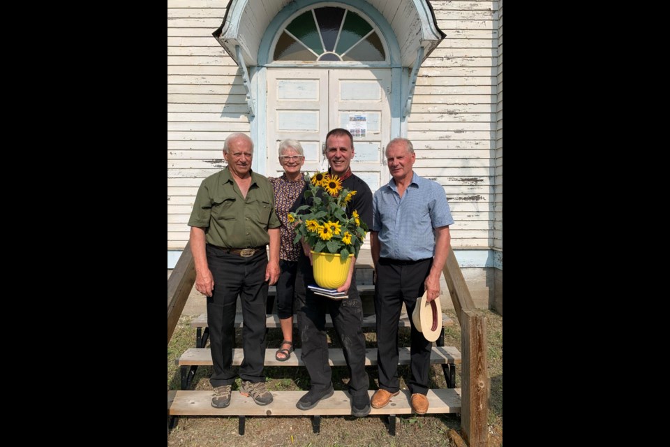 Jim Tkatchuk, Audrey Mushtaler (nee Ewanchuk) and Ray Ewanchuk presented Father Ivan Nahachewsky with a sunflower at the conclusion of Praznyk at Whitkow June 10.