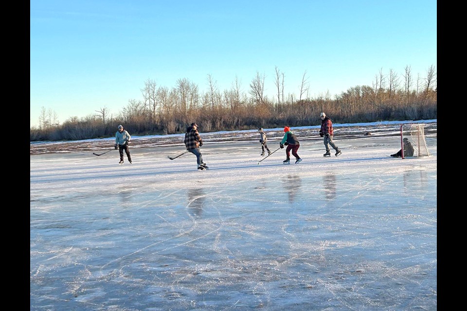 Enjoying the balmy weather, Woloshyn family men and young boys play a scrimmage game of hockey on a slough near Mayfair. Nothing like getting fresh air, exercise and fun on Boxing Day. 