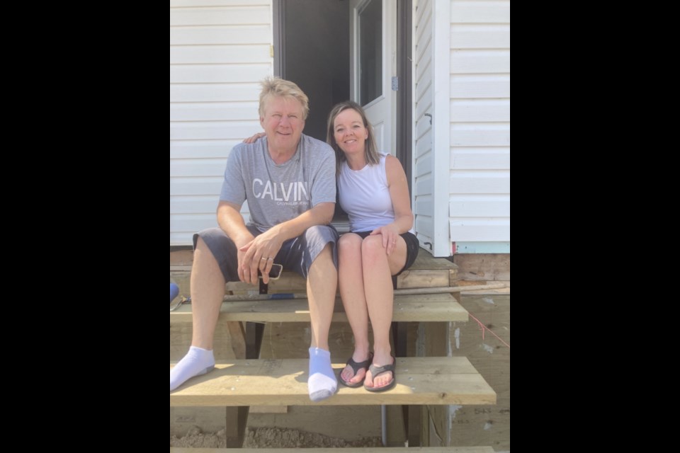 A happy couple, Ted and Carla Adamus, on the steps of their nearly complete residence on the west end of Second Avenue. They did much of the labour in preparing the prefab house's basement. Welcome to our new residents and congratulations on making their vision come true.