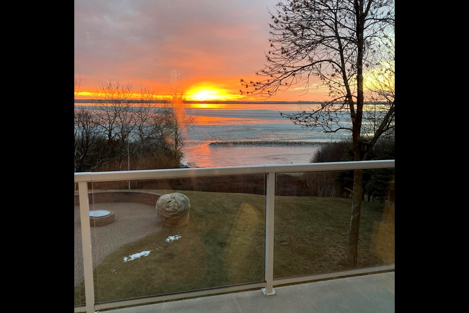 Living skies above frozen-over Jackfish Lake create a picturesque sunset.