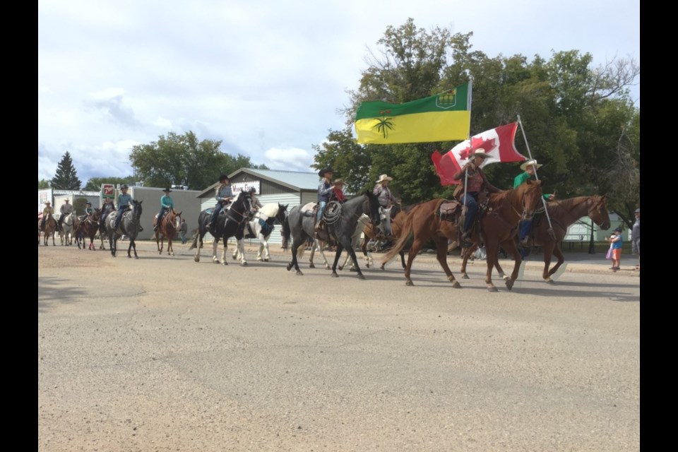 Flag bearers Dale and Diane Kieper and horseback riders leading the Radisson Ag. Fair parade. 