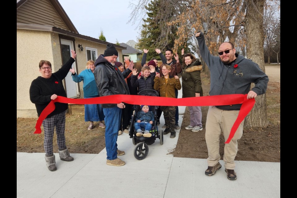 Mayor Pete Reddekopp cuts the ribbon at the newly constructed sidewalks in the Town of Radisson on Nov. 4 while Deputy Mayor Robin Baker (left) and Councillor Shawn Mitchler hold the ribbon. The town received $25,183 from the Province of Saskatchewan SGI Traffic Safety Fund this summer. 