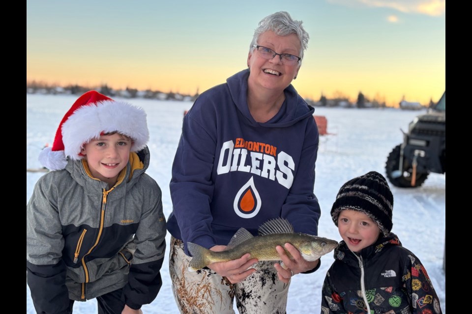 Betty Johnson, with two of her grandchildren, Finn and Kelson as they proudly show off the Walleye that she caught. It was the same fish that appeared on their monitor. 