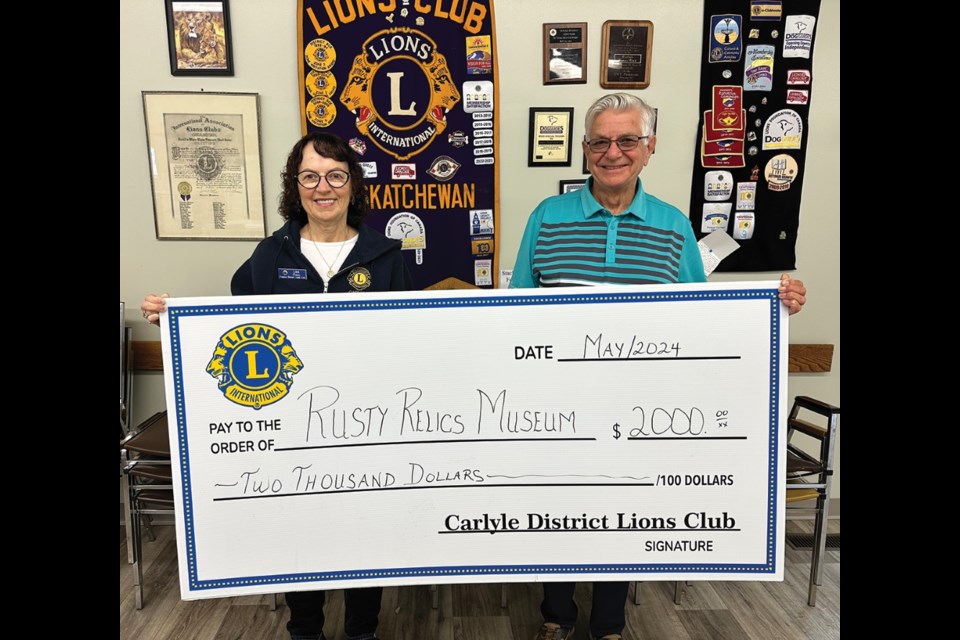 Lions club member Lois Paul presents a cheque to Rusty Relics Museum chairman Ron Paul.