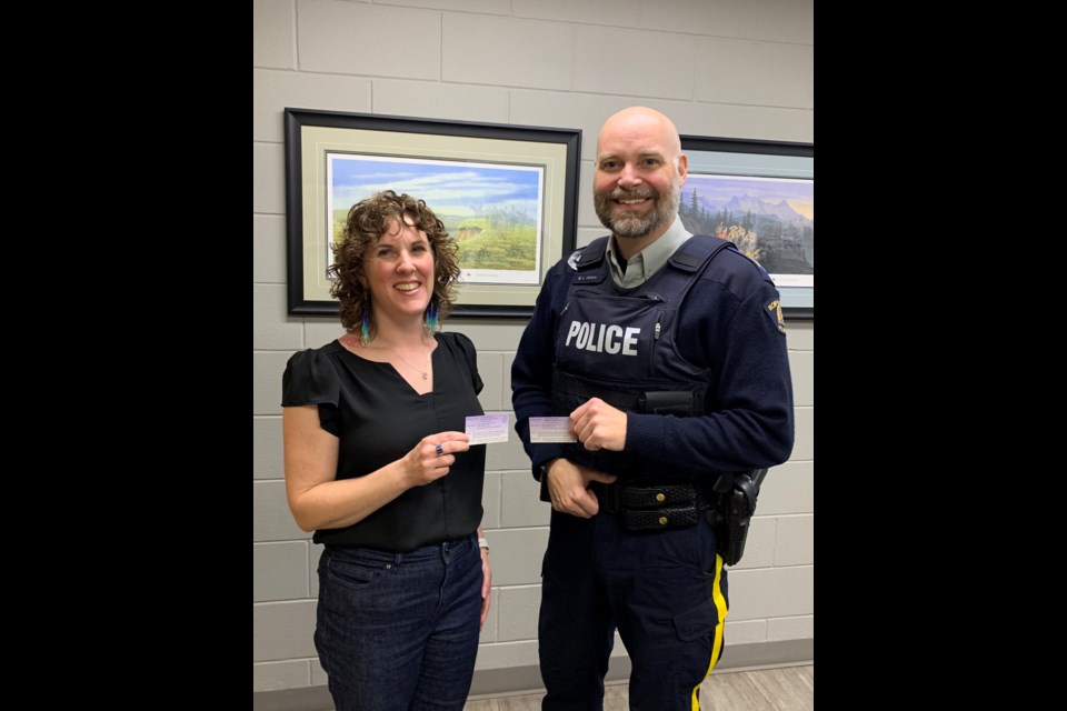 Delores LeVangie, Outreach and Education Coordinator with Shelwin House pictured here with Staff Sergeant Burton Jones and Detachment Commander of the Yorkton RCMP, holding a resource card intended for women who have been subjected to domestic violence.