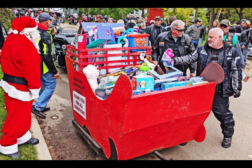 Motorcyclists who took part in the annual Toy Run bring their toy donations to the sleigh at the end of the Run in River Park.