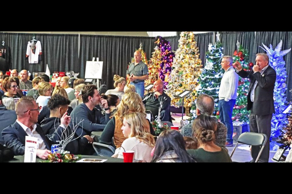 Auctioneer Winston Bailey took bids for one of the 27 decorated Christmas trees up for auction at the Family Place's Festival of Trees on Wednesday night.