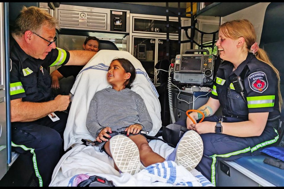 Sukhleen Kaur listened to EMTs Jason Roy, left, and Lexy Tessier, as she lay on the gurney in the back of an ambulance, during a visit by the Weyburn EMS to the 'College for Kids' program on Wednesday.