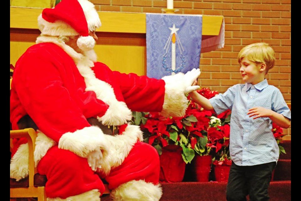 Kayson Giroux gave Santa a high-five after some persuasion from mom, at the sensory-free Santa day hosted by Inclusion Weyburn on Saturday.