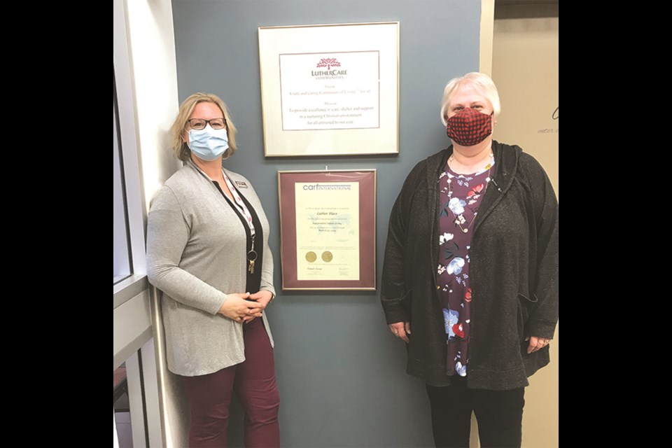 Housing Manager Melanie Harris and Sales Representative Darci Morken pose with the plaque indicating the CARF accreditation that Luther Place has achieved. Each year, seals indicating high standards of care and maintenance must be earned. 