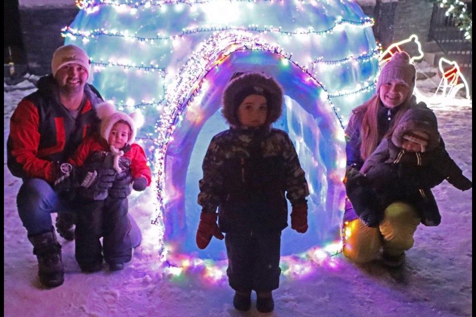 Josh and Lexie Mainil, and their children Elias, Gracie and baby Lydia, pose by their igloo, built on the front lawn of their home in Weyburn.