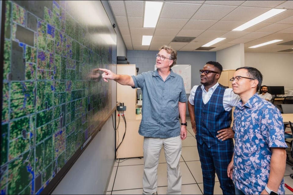 Dr. Steve Shirtliffe (PhD) shows a screen in his lab to Dr. Thaun Ha and Dr. Kwabena Nketia. 