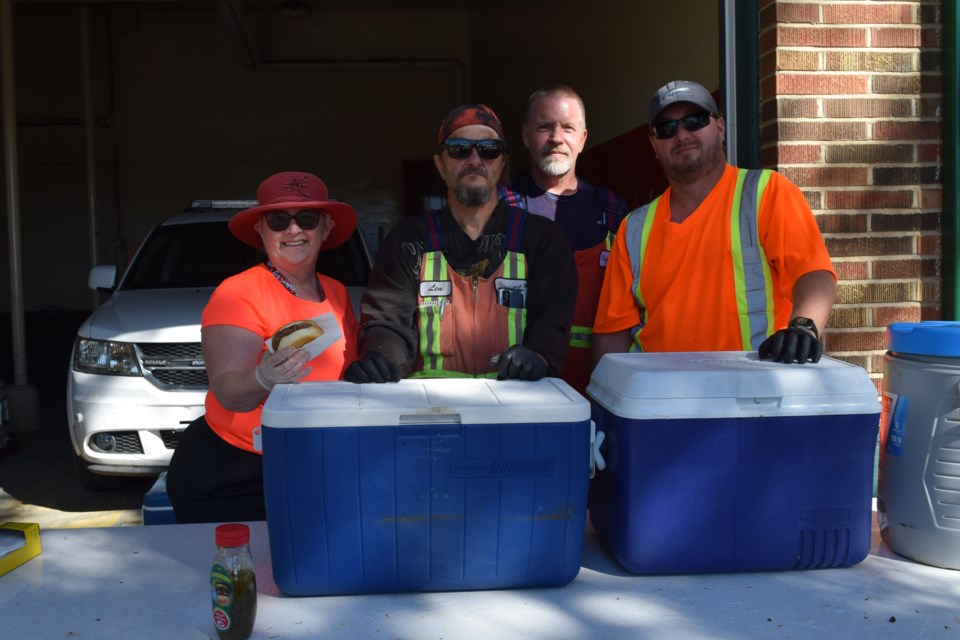 Behind the burger and drink stand were, from left, councilor Shelley Filipchuk, Len Ortman, Bryan Semeniuk, and Chris Simon.