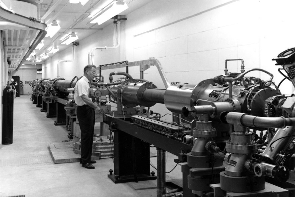 Dr. Leon Katz (PhD), director of the Saskatchewan Accelerator Laboratory, stands next to the linear accelerator in 1964. 