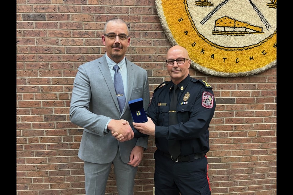 Sgt. Kevin Reed, left, accepts his 30-year bar from Estevan Police Chief Jamie Blunden. 