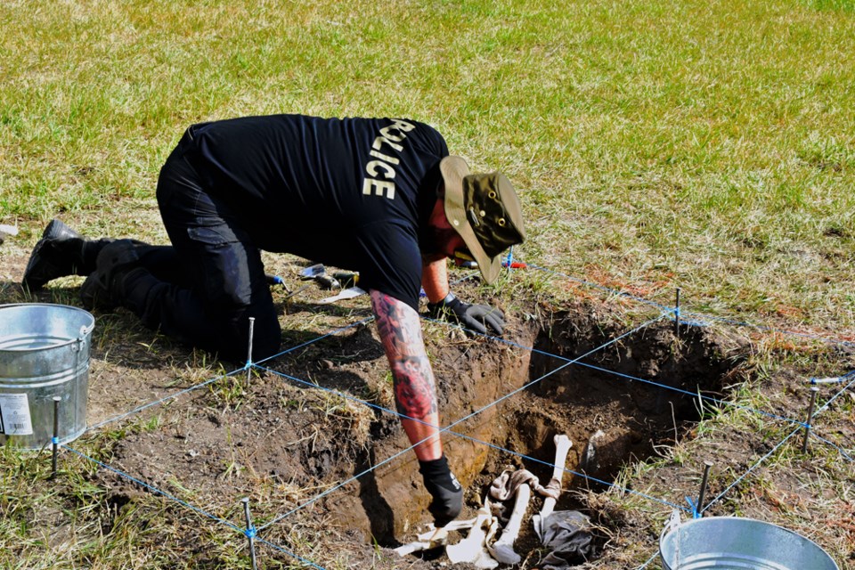 Quebec Provincial Police officer Christian Rouleau demonstrates how to properly handle evidence of human remains in a make-shift grave site.