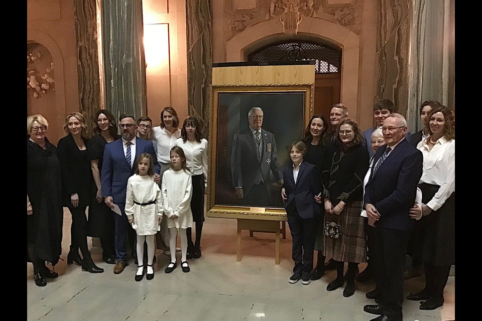 Family members of the late Tom Molloy gather around the official portrait of the former Lieutenant Governor unveiled Thursday.