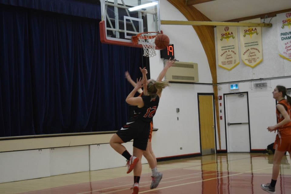 Bree Woloshyn of the Cougars (dark uniforms) somehow executed this off-balance shot after driving to the basket in a game against the visiting Yorkton Regional High School Raiders on March 9.