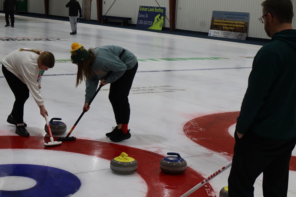 At the Canora Christmas Bonspiel held on Dec. 27 and 28, from left, Aubrey Wilson and her sister Abby swept this rock into the rings, while Terry Wilson provided direction and encouragement for his daughters.