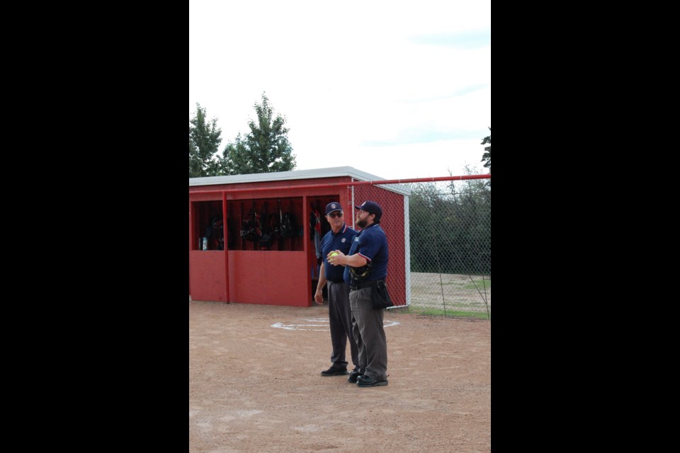 Trevor Green, left, touches base with fellow umpire before the first game of the U17 C Provincial tournament in Macklin, July 5-7.