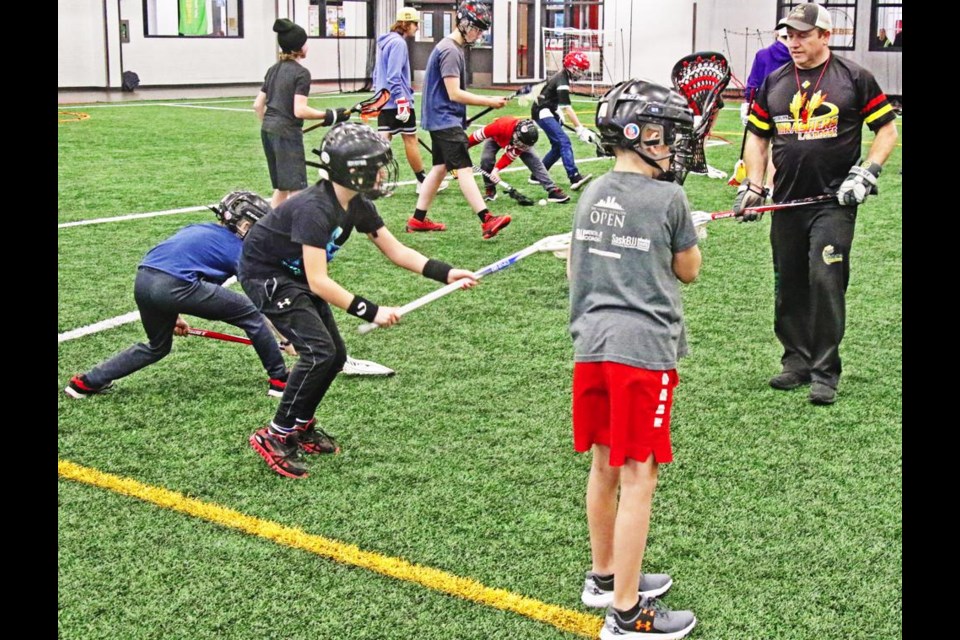 Coach Chuck Hignett, right, of the Weyburn Lacrosse Association showed an older group of children how to properly handle a lacrosse racket, at a try-out evening for the sport.