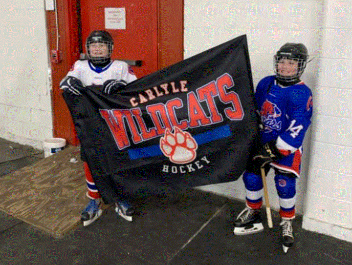 From left, Finely Sauter and Hadley Blaise, both from the U11 Cougars carried the Wildcats Battle Flag to celebrate female hockey in Carlyle. 