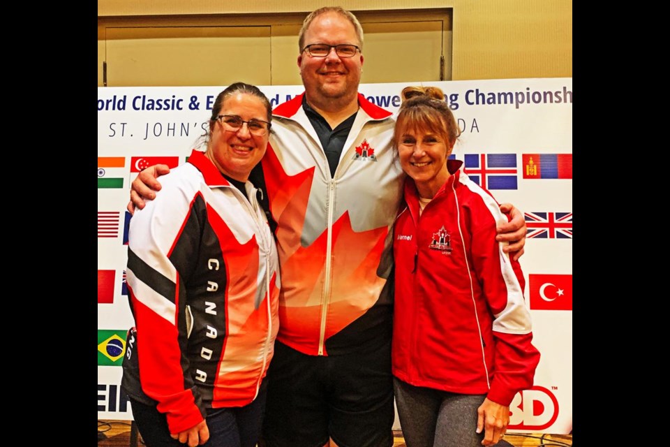 Heidi Fowler, left, and Marnel Spencer gathered with their coach, Ryan Fowler, after winning gold and silver at the World Classic powerlifting championships in St. John's, Nfld.