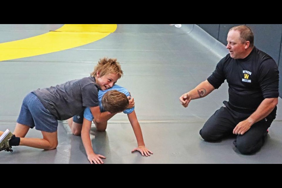 Wrestling coach Greg Kiraly gave some pointers to two boys on how to take down an opponent, during the learn-to-wrestle clinic on Saturday at the Elgin gym.