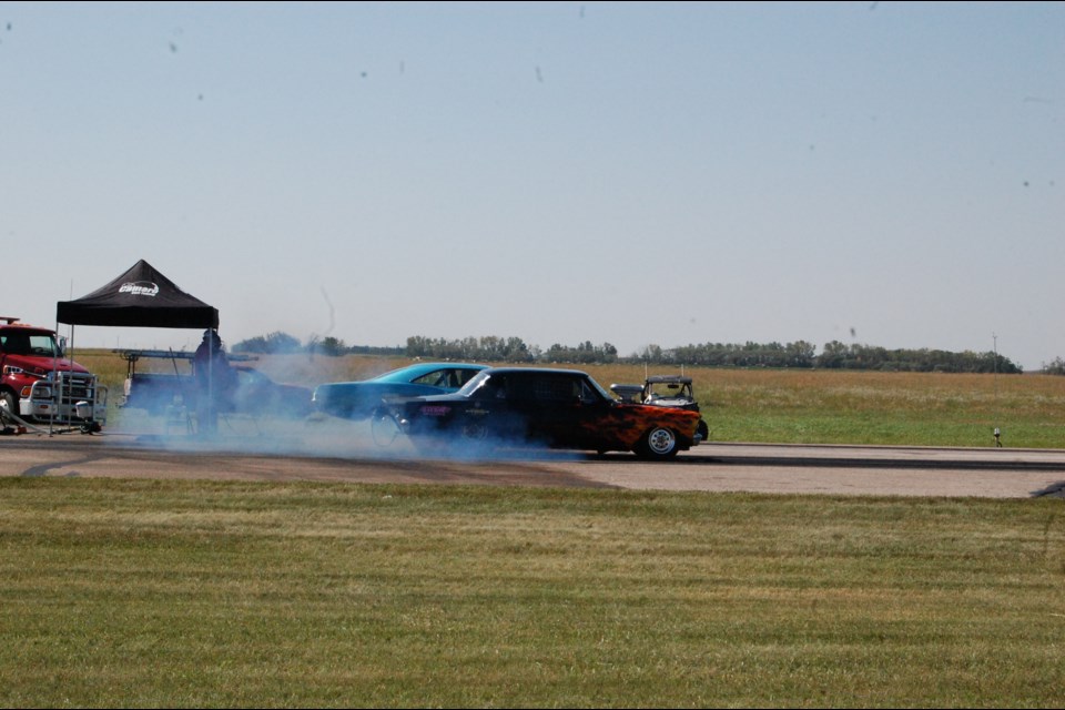 Two cars heat up their tires prior to racing, increasing the grip on the pavement.