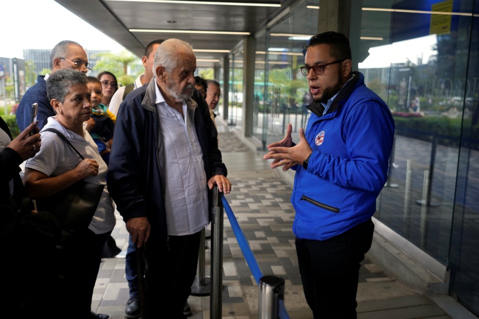 A U.S. consular official explains to people with scheduled visa document submissions that their appointments were canceled due to Colombian President Gustavo Petro's refusal to accept repatriation flights of Colombian citizens from the U.S., at a U.S. Embassy Applicant Service Center in Bogota, Colombia, Monday, Jan. 27, 2025. (AP Photo/Fernando Vergara)