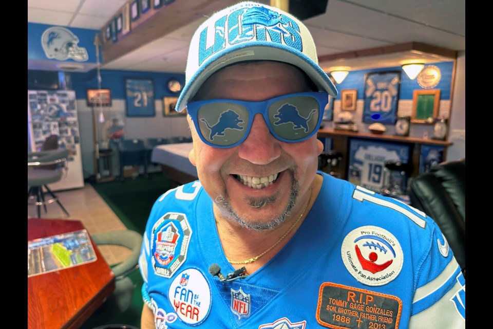 Detroit Lions NFL football fan Rob Gonzales smiles while wearing Lions sunglasses in the basement of his home Thursday, Jan. 16, 2025, in Frenchtown Township, Mich. (AP Photo/Mike Householder)