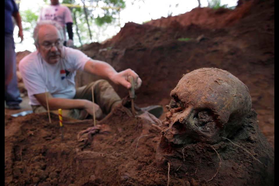 FILE - Rogelio Goiburu, a member of Paraguay's Truth and Justice Commission, looks at skeletal remains found buried as they are excavated at the National Police Special Forces headquarters in Asuncion, Paraguay, March 19, 2013. Goiburu's father, an opponent of the Stroessner dictatorship, went missing in 1977. (AP Photo/Jorge Saenz, File)