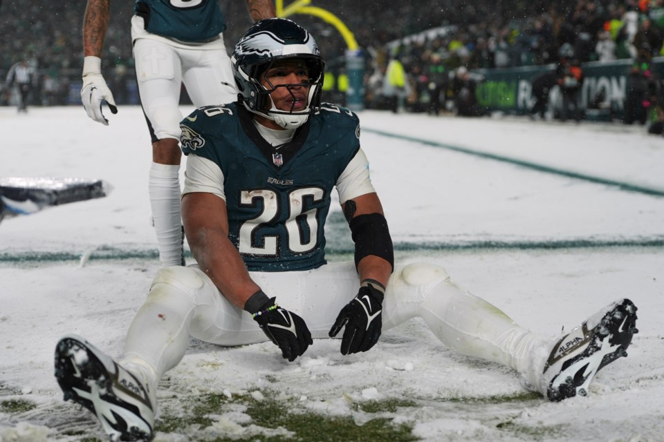 Philadelphia Eagles running back Saquon Barkley (26) sits in the snow as he celebrates his touchdown during the second half of an NFL football NFC divisional playoff game against the Los Angeles Rams on Sunday, Jan. 19, 2025, in Philadelphia. (AP Photo/Matt Slocum)