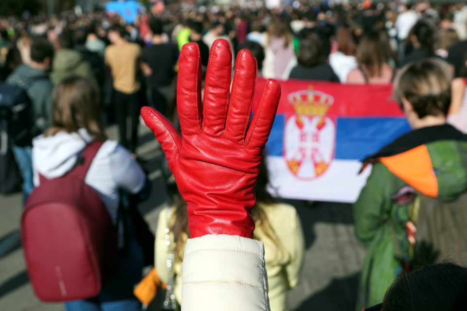 A woman raises a red glove symbolizing blood during a student-led 24 hour block on an intersection to protest the deaths of 15 people killed in the November collapse of a train station canopy, in Belgrade, Serbia, Monday, Jan. 27, 2025. (AP Photo/Darko Vojinovic)