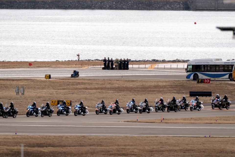 Police officers escort buses carrying family members of the victims of a mid-air collision between an American Airlines jet and an Army helicopter to runway 33 near the wreckage site in the Potomac River at Ronald Reagan Washington National Airport, Sunday, Feb. 2, 2025, in Arlington, Va. (AP Photo/Jose Luis Magana)