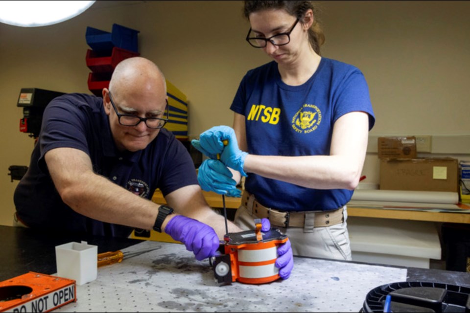 In this image provided by the National Transportation Safety Board, NTSB investigators examine cockpit voice recorder and flight data recorder in Washington, Thursday, Jan. 30, 2025, recovered from the American Airlines passenger jet that crashed with an Army helicopter Wednesday night near Ronald Reagan Washington National Airport. (NTSB via AP)