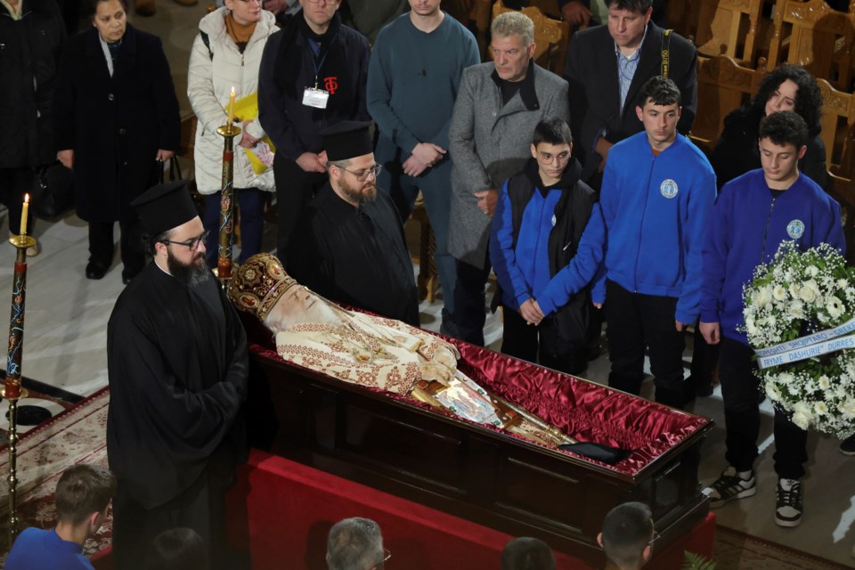 Greek Orthodox priests stand next to the casket of the late Archbishop Anastasios of Tirana, Durres and All Albania as people pay their respects during a religious ceremony, a day before his funeral, inside the Cathedral of the Resurrection of Christ, in Tirana, Albania, Wednesday, Jan. 29, 2025. (AP Photo/Vlasov Sulaj)