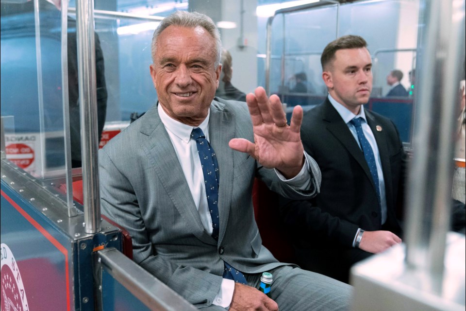 FILE - Robert F. Kennedy Jr., waves to reporters as he rides the train to go to meet with Sen. John Thune, R-S.D. at the Capitol in Washington, Dec. 17, 2024. (AP Photo/Jose Luis Magana, File)