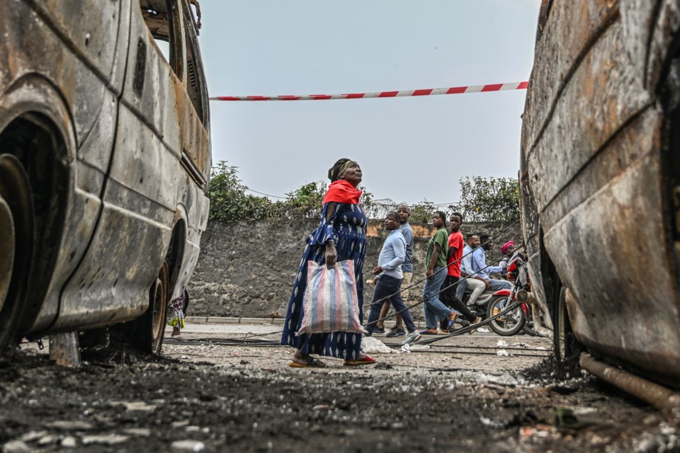 Residents walk by charred vehicles in Goma, Democratic republic of the Congo, Friday, Jan. 31, 2025. (AP Photo/Moses Sawasawa)