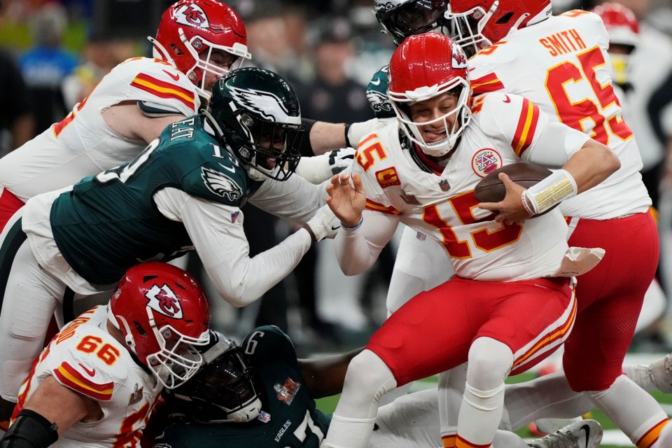 Kansas City Chiefs quarterback Patrick Mahomes (15) tries to avoid the reach of Philadelphia Eagles linebacker Josh Sweat, left, during the first half of the NFL Super Bowl 59 football game, Sunday, Feb. 9, 2025, in New Orleans. (AP Photo/Brynn Anderson)