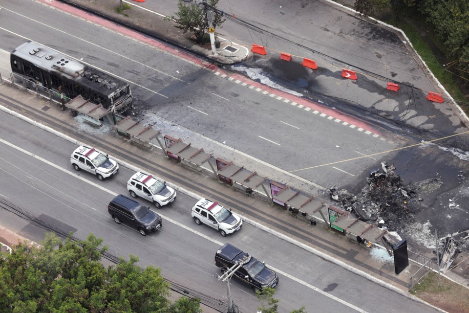 The crash site of a small plane, right, that burned a bus, left, covers an avenue in Sao Paulo, Friday, Feb. 7, 2025. (AP Photo/Ettore Chiereguini)