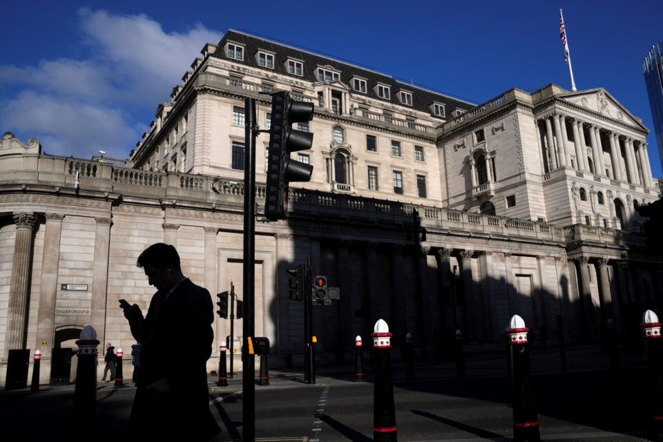 A man is silhouetted as he looks on his phone in front of the Bank of England in London, Thursday, Feb. 6, 2025 which is widely expected to cut interest rates for the third time in six months later Thursday. (AP Photo/Kin Cheung)