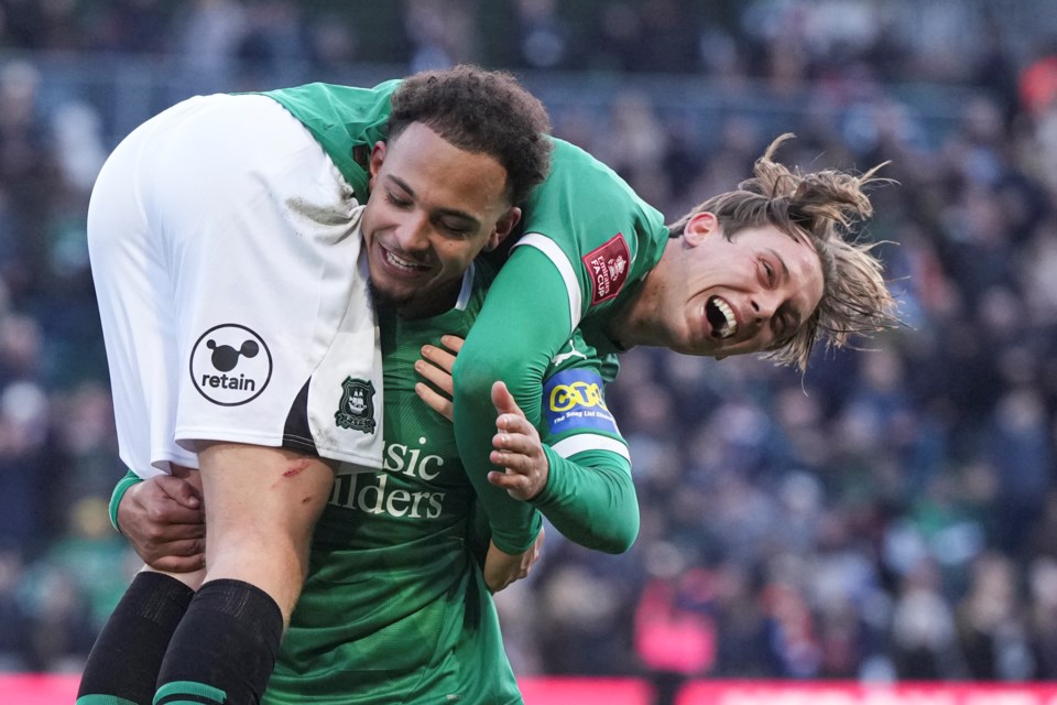 Plymouth Argyle's Callum Wright is carried by Matthew Sorinola as they celebrate after the English FA Cup fourth round soccer match between Plymouth Argyle and Liverpool at Home Park stadium in Plymouth, England, Sunday, Feb. 9, 2025. (AP Photo/Alastair Grant)