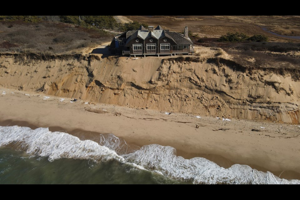 A home sits atop of a sandy bluff overlooking a beach in Wellfleet, Mass., Monday, Jan. 27, 2025. (AP Photo/Andre Muggiati)