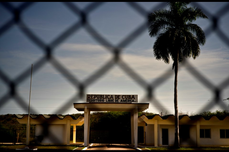 FILE - In this photo reviewed by U.S. military officials, a building in Cuba carries the Spanish message "Republic of Cuba. Free American Territory," behind a gate marking the border with the U.S. Guantanamo Bay naval base in Cuba, June 6, 2018. (AP Photo/Ramon Espinosa, File)