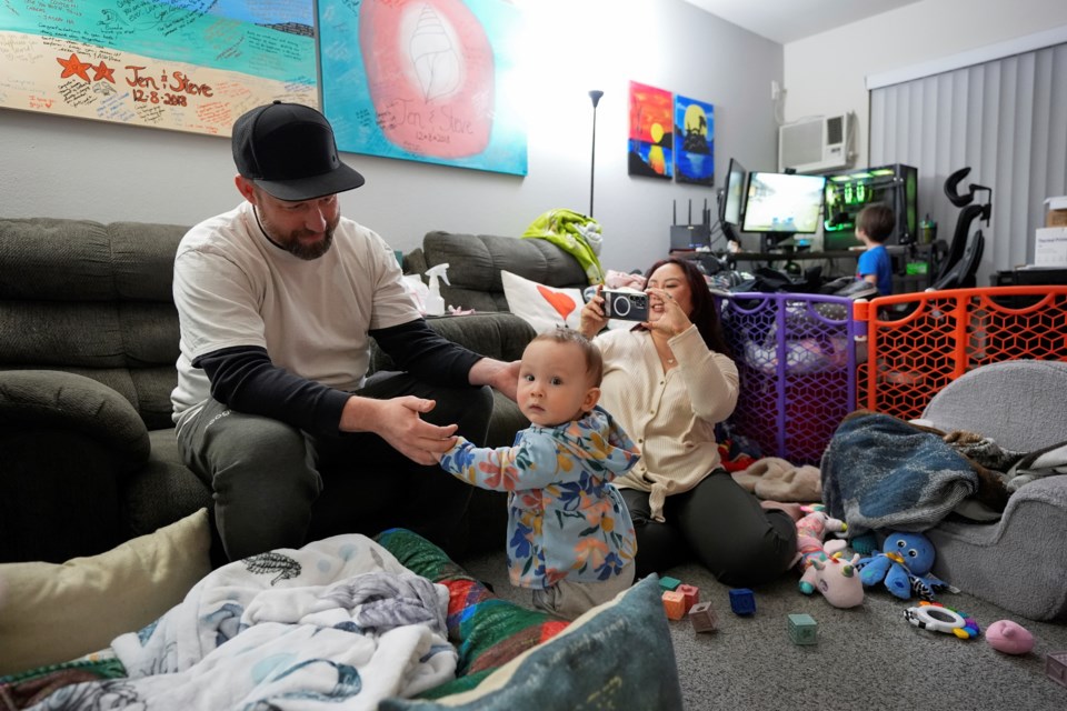 Steve Petersen, left, and his wife Jennifer watch as their daughter Carolynn tries to stand inside their apartment in Campbell, Calif., Wednesday, Jan. 15, 2025. (AP Photo/Godofredo A. Vásquez)