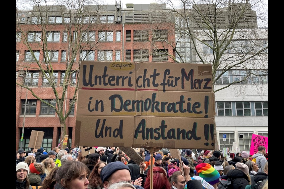 People gather to protest against the Far Right, in Cologne, Germany, Saturday Jan. 25, 2025. Banner reads: "Immediate lessons for Merz in democracy and decency". (Christoph Driessen/dpa via AP)