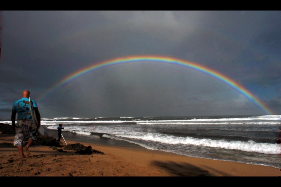 FILE - Professional surfers make their way to the water while a large rainbow crosses the ocean during the Pro Hawaii surfing contest at Ali'i Beach in Haleiwa, Hawaii, Nov. 18, 2005. (AP Photo/Lucy Pemoni, File)