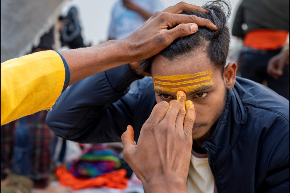 A Hindu devotee gets a sacred mark on his forehead after bathing at the confluence of the Ganges, the Yamuna, and the Saraswati rivers during the 45-day-long Maha Kumbh festival in Prayagraj, India, Tuesday, Jan. 14, 2025. (AP Photo/Ashwini Bhatia)