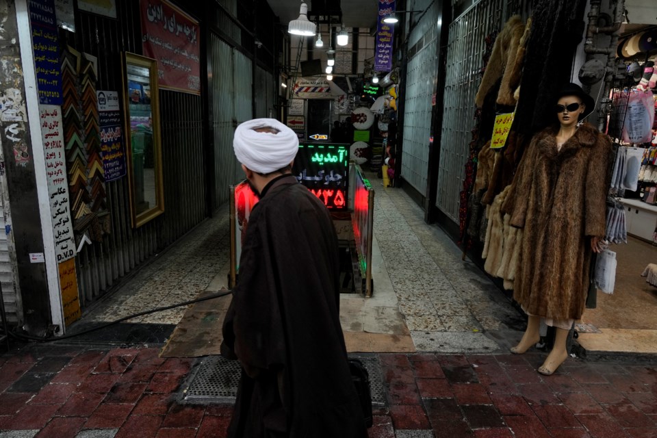 A cleric walks in front of a shopping center in northern Tehran, Iran, Monday, Jan. 27, 2025. (AP Photo/Vahid Salemi)